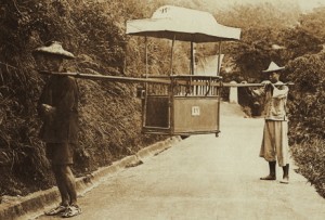 Two Chinese coolies holding an empty sedan chair