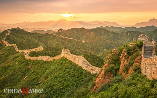 The Great Wall of China snaking through the mountains at sunset